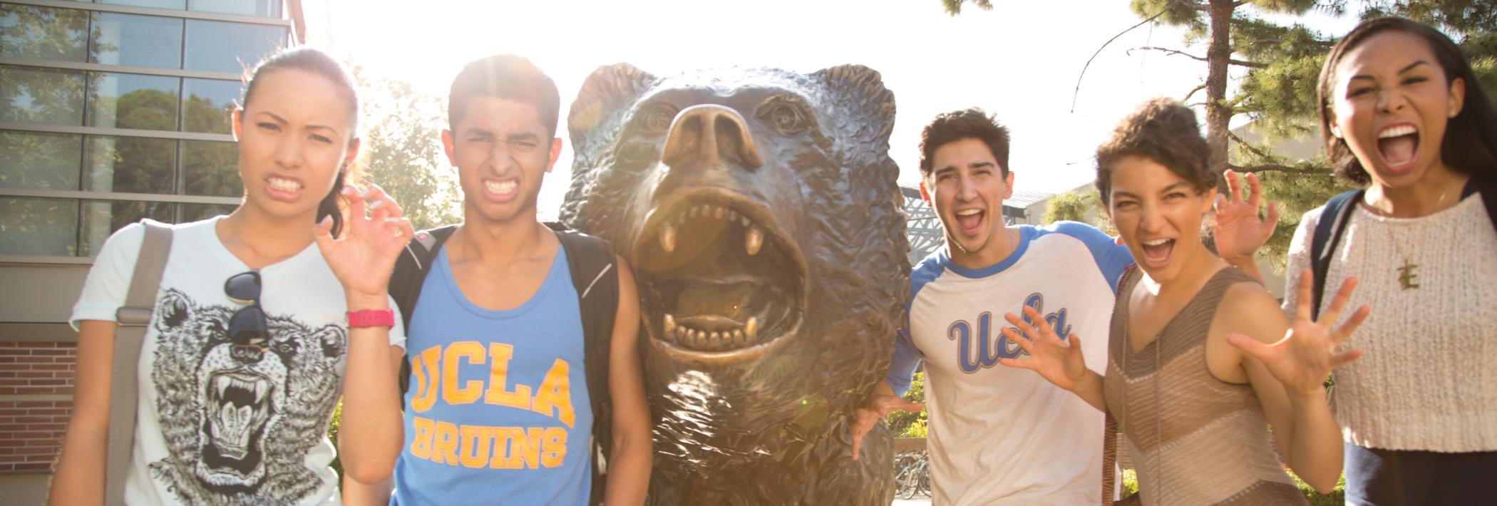 Five students strike a pose beside the Bruin Bear statue.